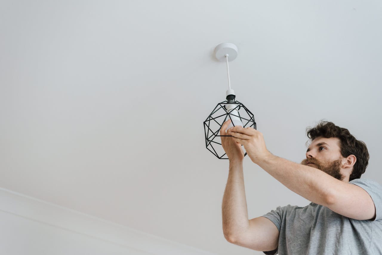 services-03 A professional electrician skillfully installing a modern geometric ceiling lamp indoors.