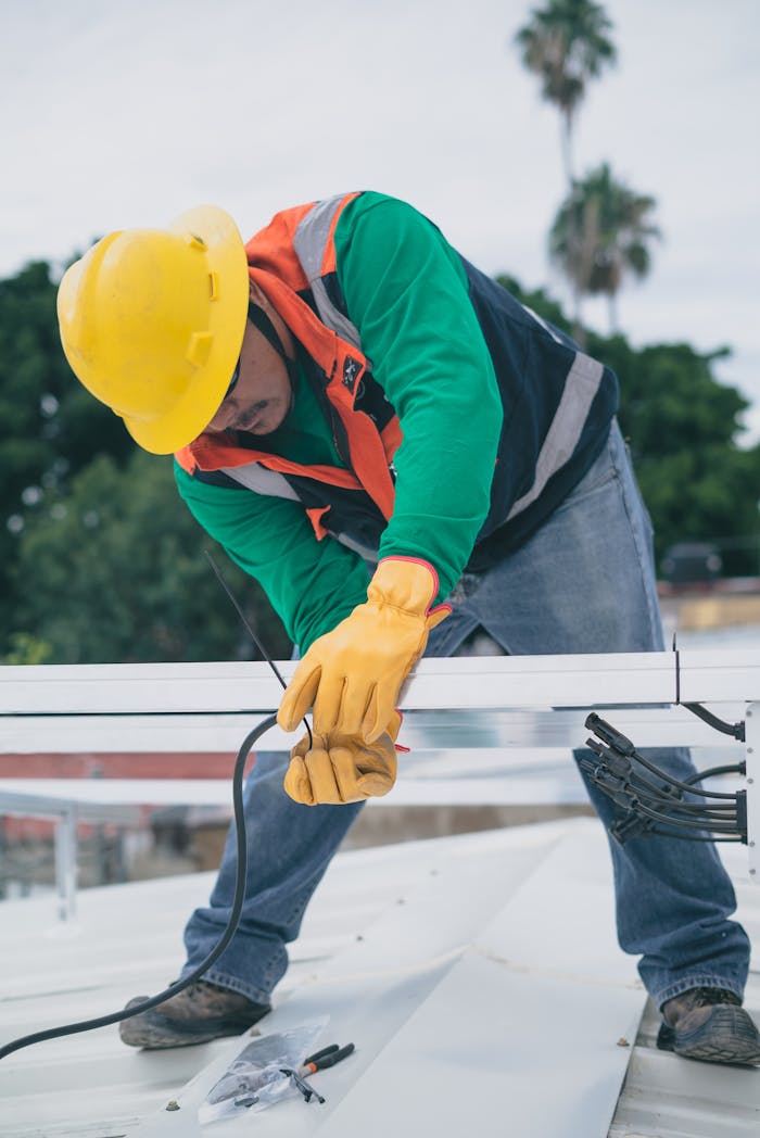 why-choose-us A construction worker wearing PPE installs electrical equipment on a roof.